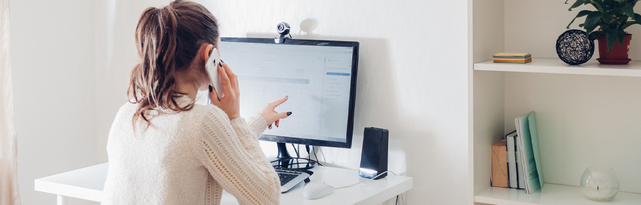 Woman talking on phone and looking at computer monitor