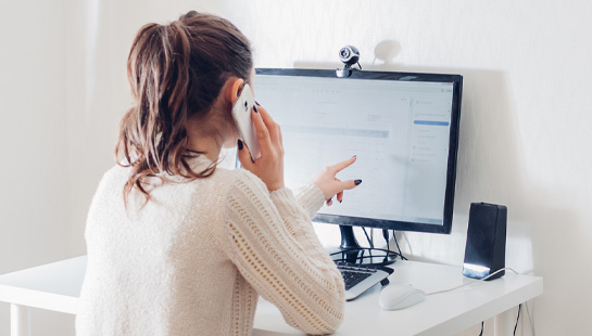 Woman talking on phone and looking at computer monitor