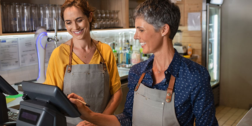 two women working at register in a restaurant setting