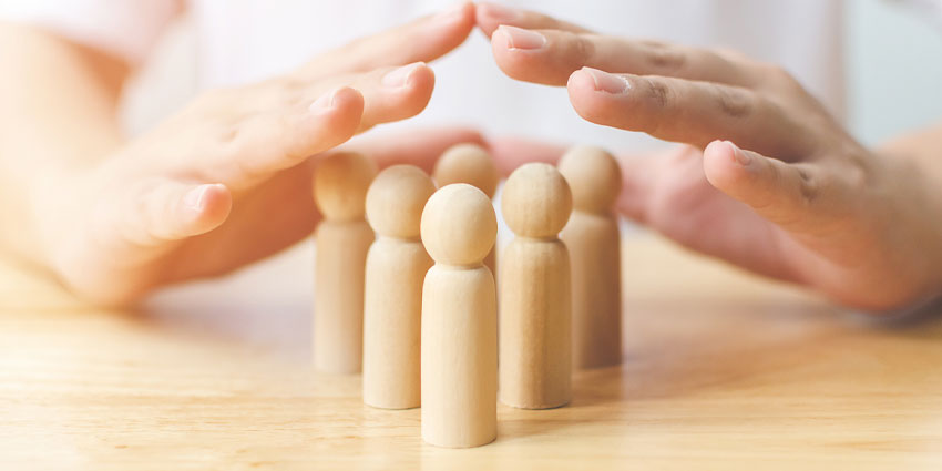 hands protecting wooden people